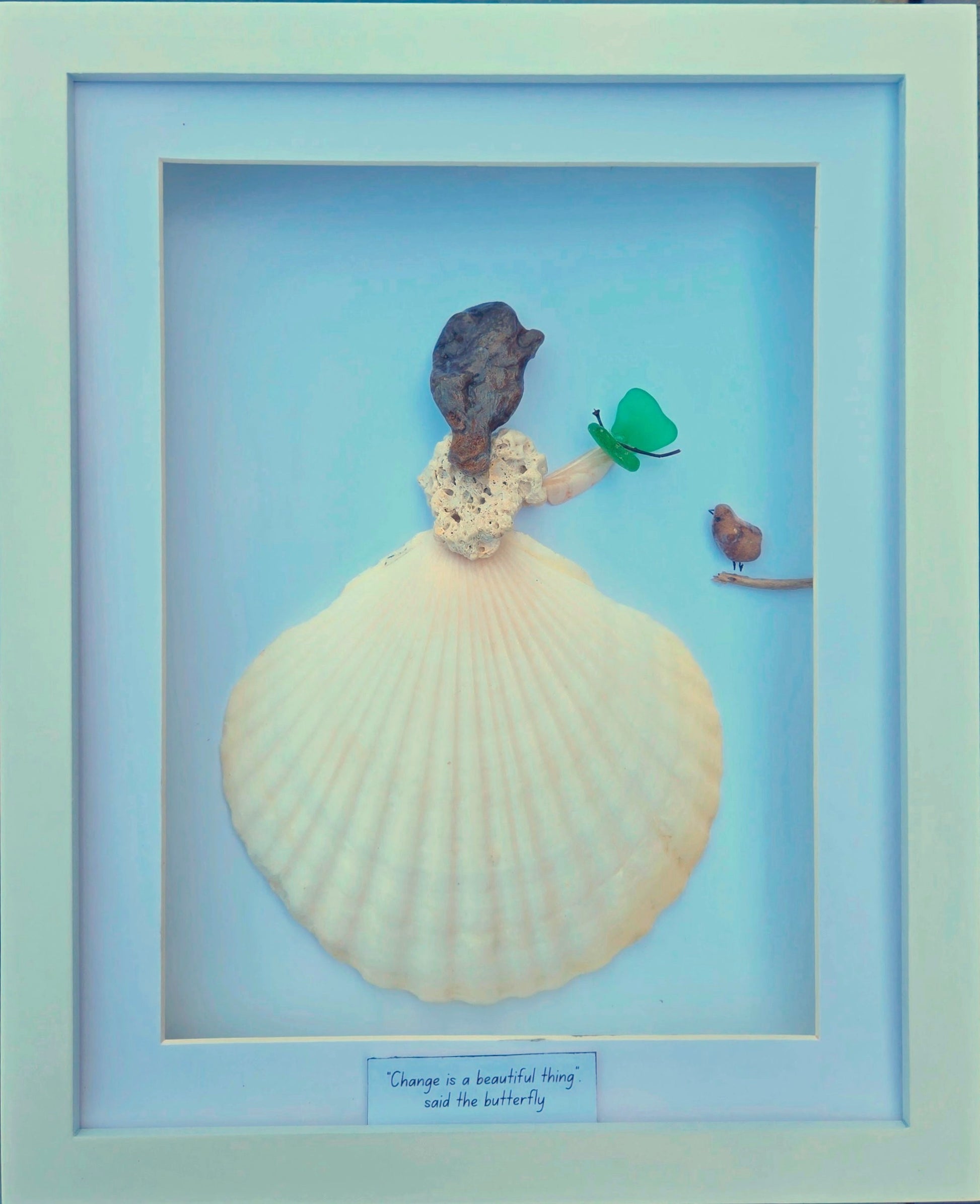 “Change is a Beautiful Thing”
A one-of-a-kind artwork celebrating growth and transformation. The figure wears a flowing gown made from a seashell found in Mexico, with coral from Cuba as her bodice. Her profile is shaped by a naturally sculpted Lake Huron stone, as if nature itself carved her hair and features. She holds a vibrant green sea glass butterfly, while a tiny bird perches nearby on a branch.
Accompanied by the words “Change is a beautiful thing, said the butterfly,” this piece is a meaningful gi