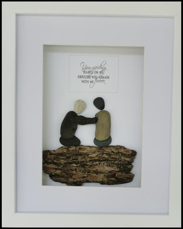 A framed sculpture of two figures, one sitting and the other standing, with their hands on each other's shoulders, surrounded by text that appears to be a quote.