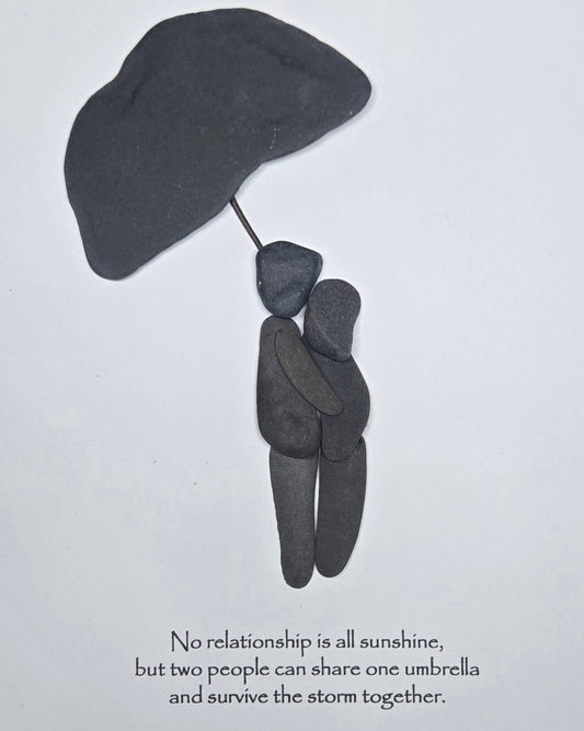 Handmade shale stone couple artwork showing two people standing together beneath an umbrella.